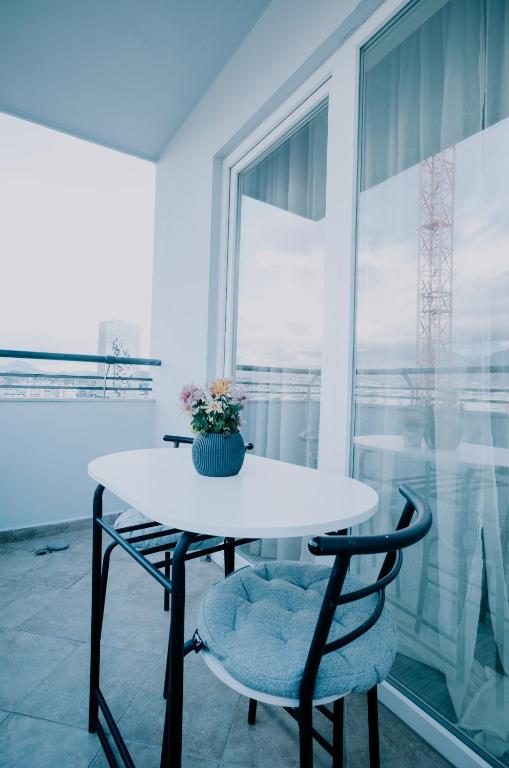 a white table with two chairs and a vase with flowers at Elrea Living 2 Central 1BR with Dajti & Skyline View in Tirana