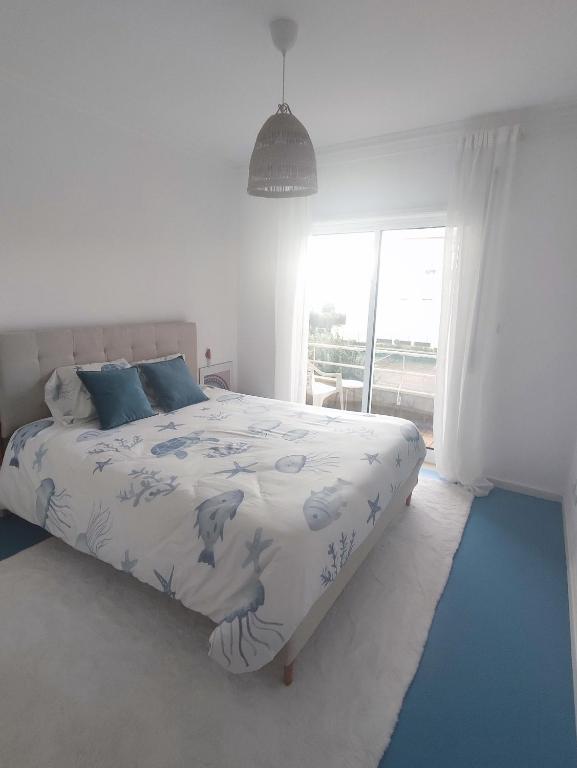a white bedroom with a bed with blue pillows at Azurara Beach Nest in Azurara