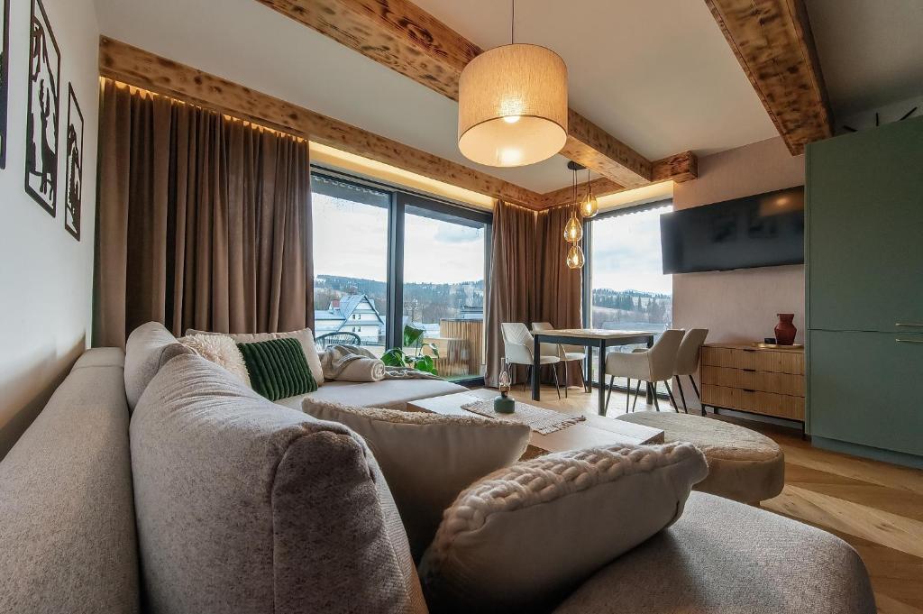 a living room with a couch and a table at Allure Chalet, z prywatnym jacuzzi, z widokiem na góry in Dzianisz