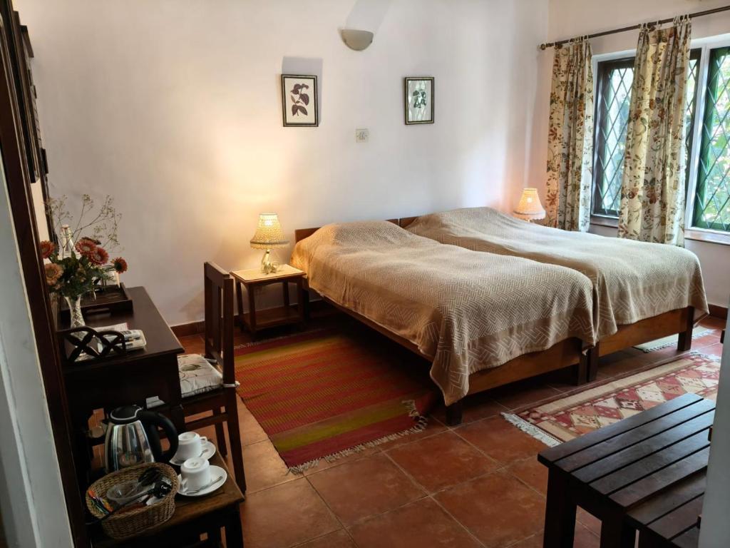 a bedroom with a bed and a table and two windows at Gitanjali Homestay in Mysore