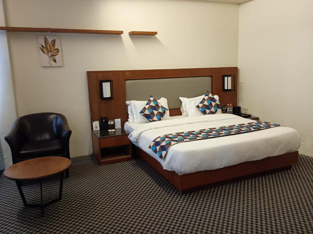 a hotel room with a bed and a chair at Lords Inn Jamnagar -Motikhavdi in Jamnagar