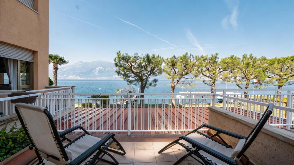 two chairs sitting on a balcony overlooking the ocean at Lake Apartment by GardaDoma in Brenzone sul Garda