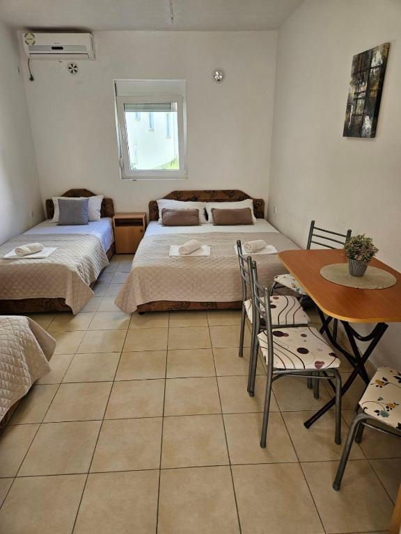 a room with two beds and a table and chairs at Apartmani Vista Čanj in Čanj