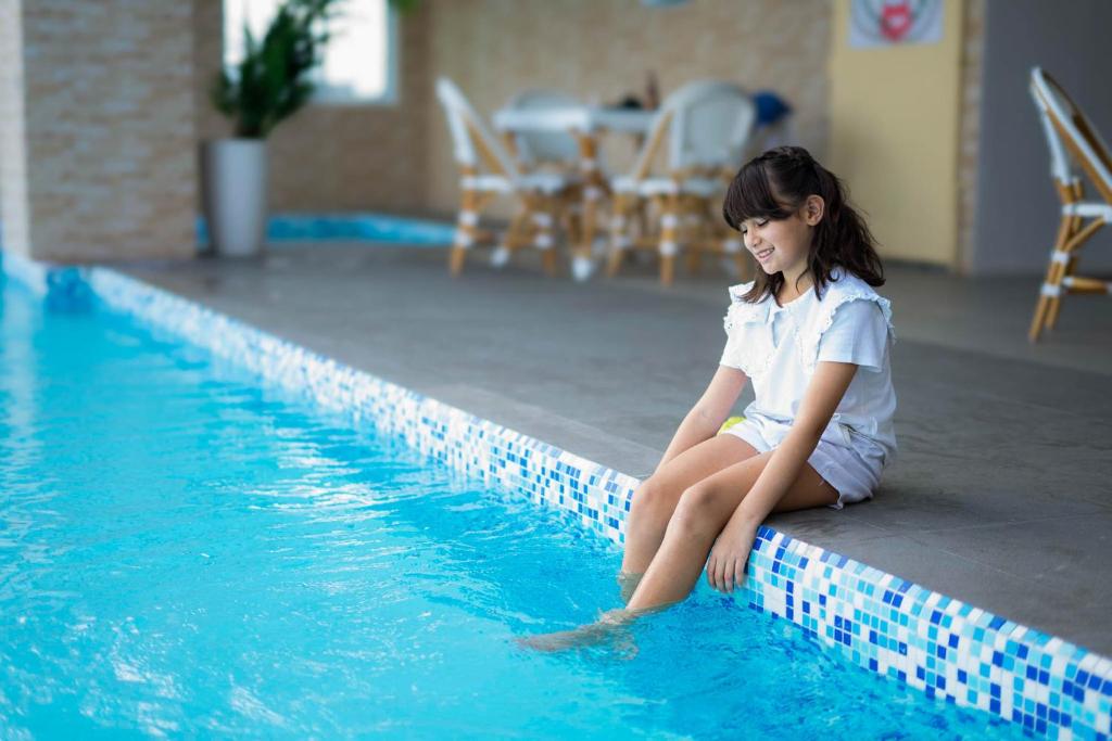 a young girl sitting next to a swimming pool at Diane Residences in Mabolo