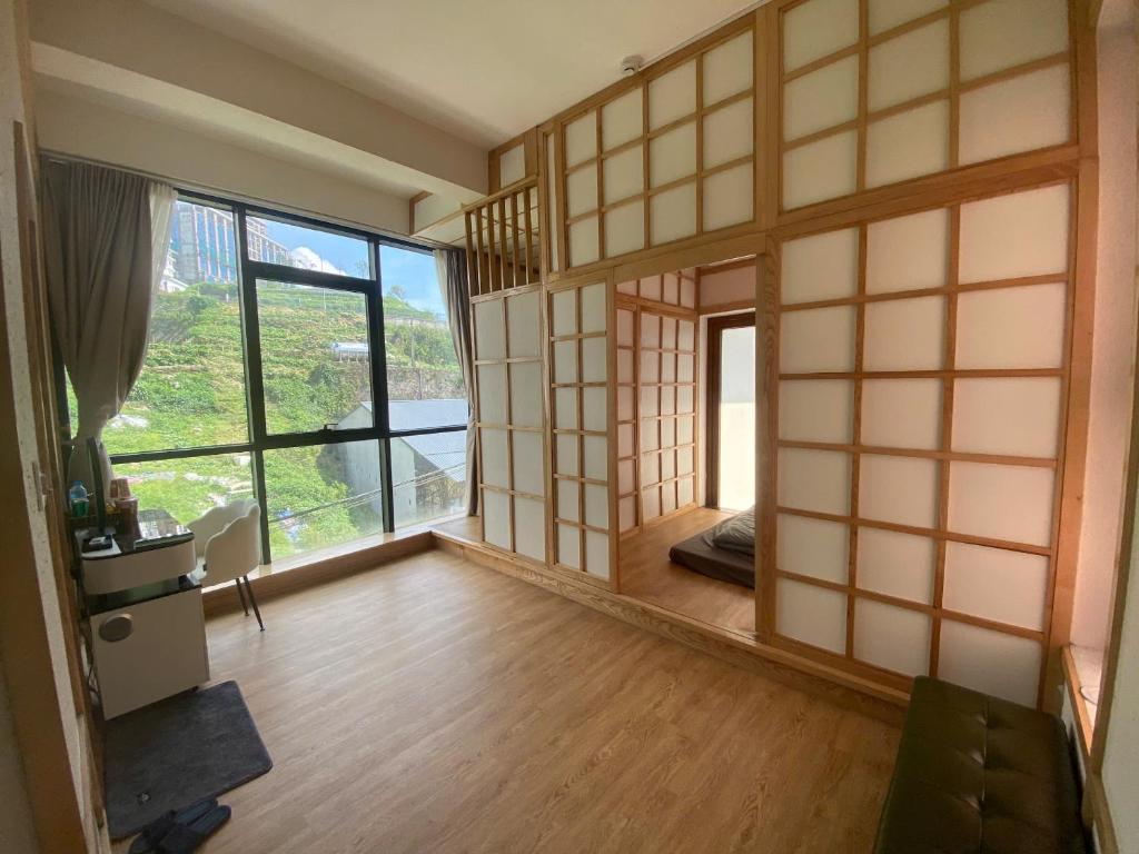 a living room with a large window and a room with wooden floors at Lexe Palace Tam Dao in Tam Ðảo