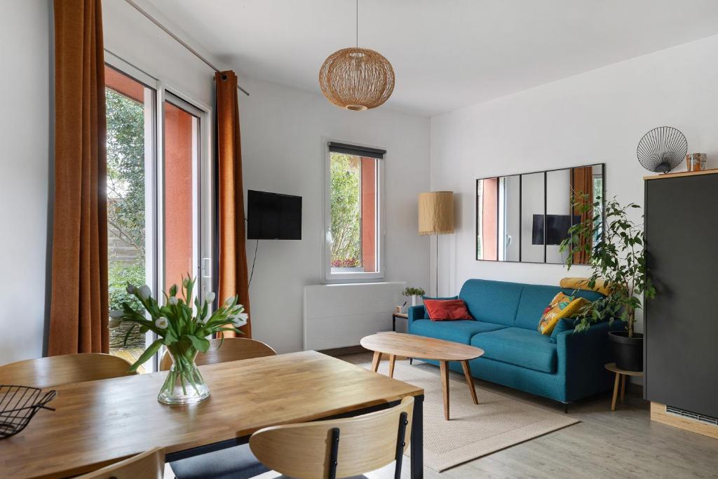 a living room with a blue couch and a table at A L'orée D'angers - Terra Botanica in Avrillé