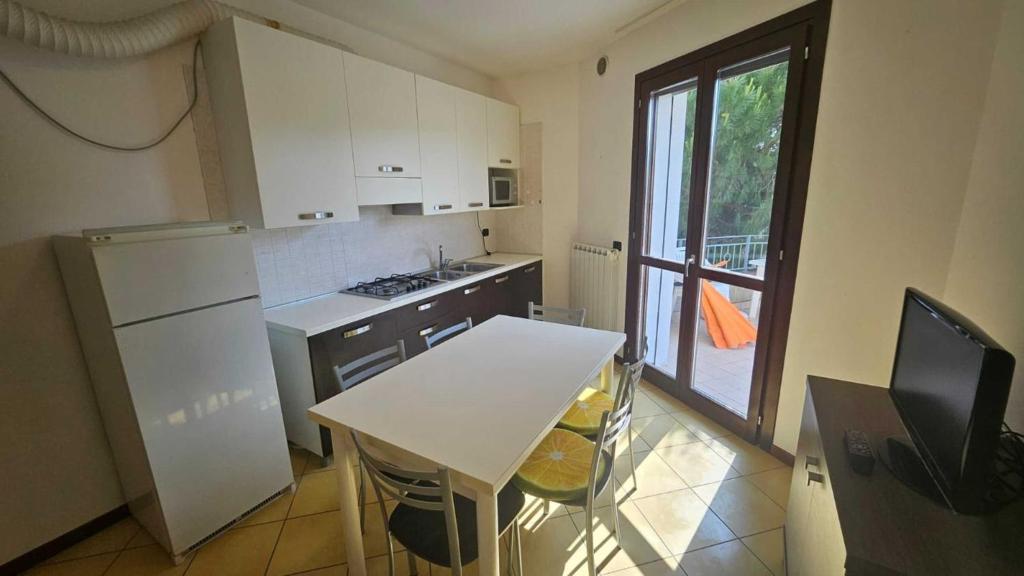 a kitchen with a table and a white refrigerator at Familiar apartment with terrace in Rosolina in Rosolina Mare