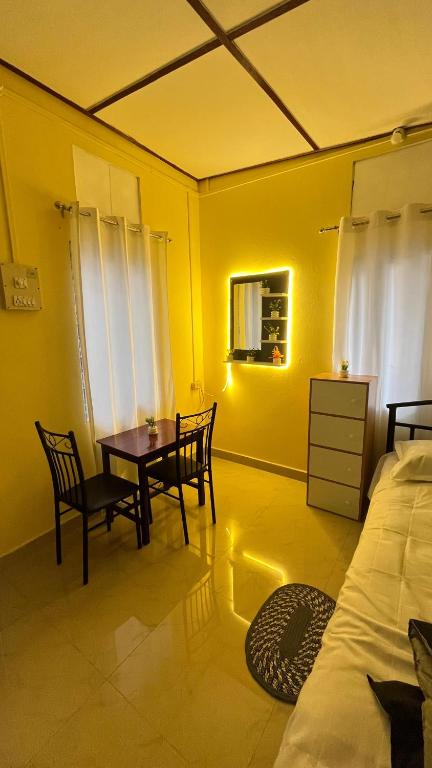 a bedroom with a table and chairs and a bed at Niroda homestay in Jorhat