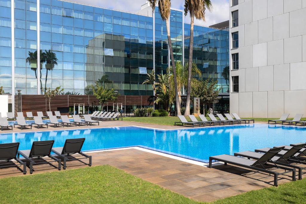 a swimming pool with lounge chairs and a building at Hotel SB BCN Events 4* Sup in Castelldefels
