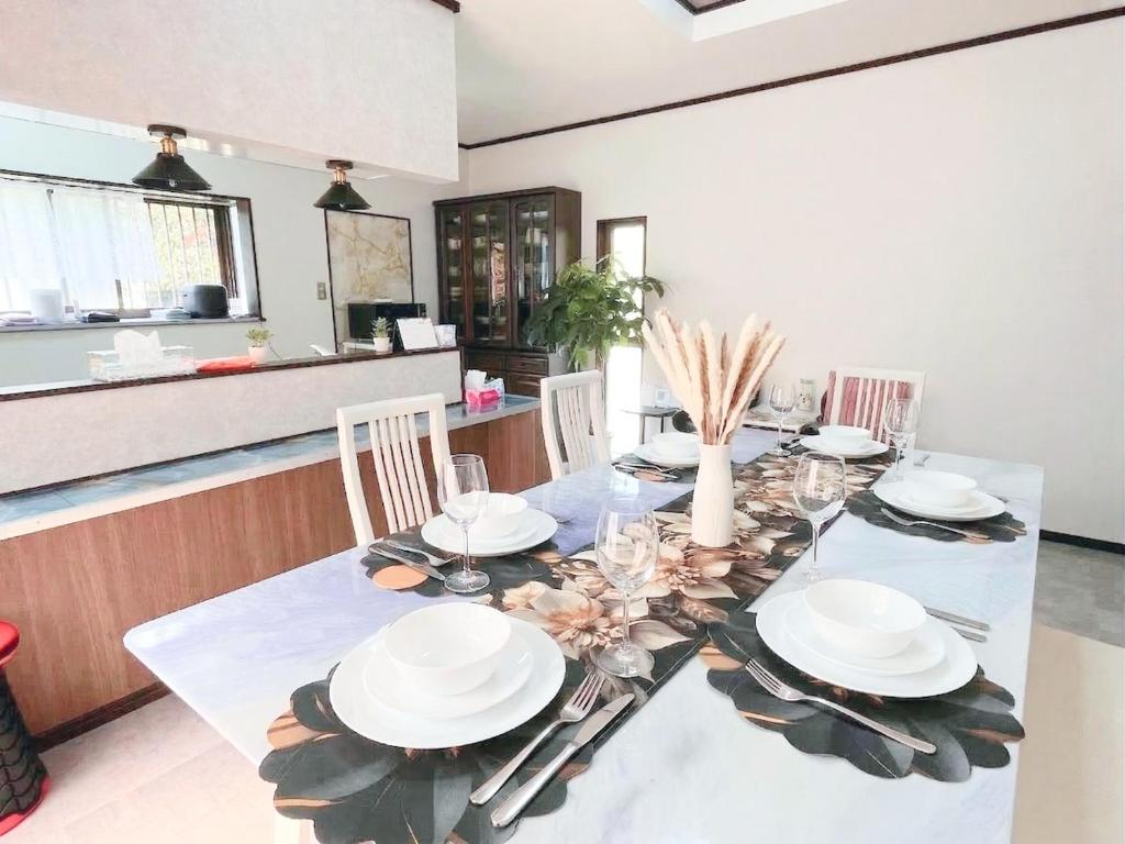 a dining room with a table with plates and glasses at 民泊 みづき 一棟貸し in Ibusuki