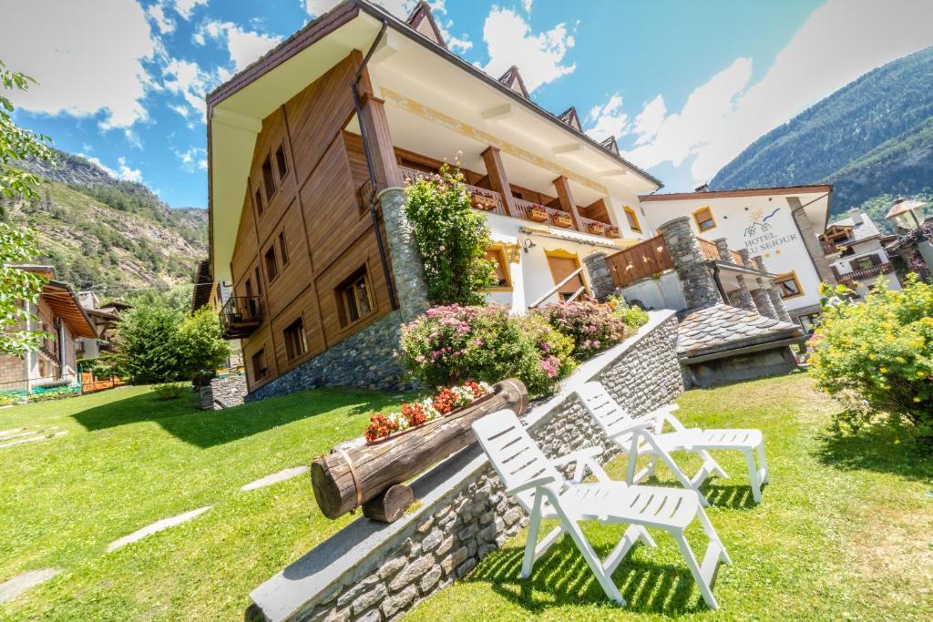 a house with two lawn chairs in front of it at Hotel Beau Sejour Pré-Saint-Didier in Pré-Saint-Didier
