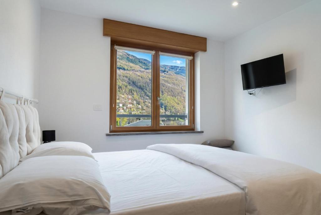a bedroom with a white bed and a window at Alla Rupe 8 - bilocale con vista sulle Alpi in Grosotto