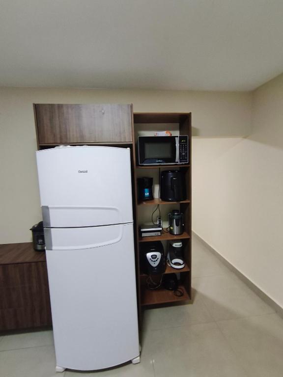 a white refrigerator in a room with a microwave at Casa Marco in Anápolis