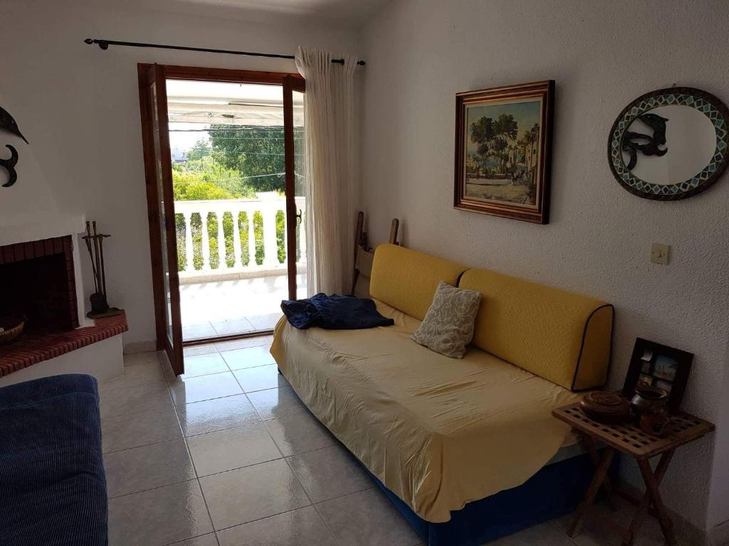 a living room with a yellow couch in front of a door at Airy and cosy summer flat in Siviri