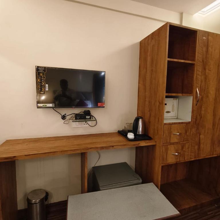 a room with a desk with a television on a wall at Sienna Suites in Navi Mumbai