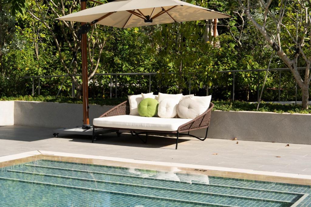 a wicker couch with pillows sitting next to a pool at The Initial Sama Serviced Residences in Singapore