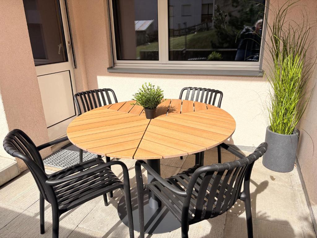 a wooden table and chairs on a patio at Ambiente Appartement C2 - moderne Ferienwohnung mit Terrasse in Leukerbad in Leukerbad