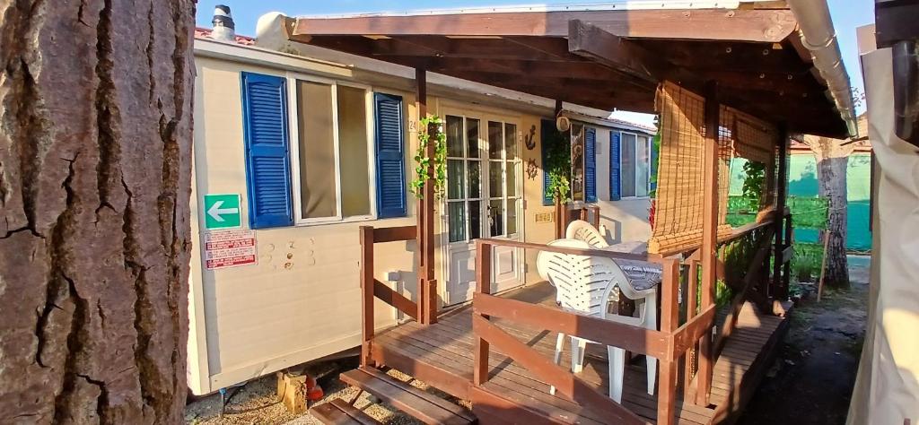 a tiny house with a porch next to a tree at GoldenSand mobilehome in Lido di Dante