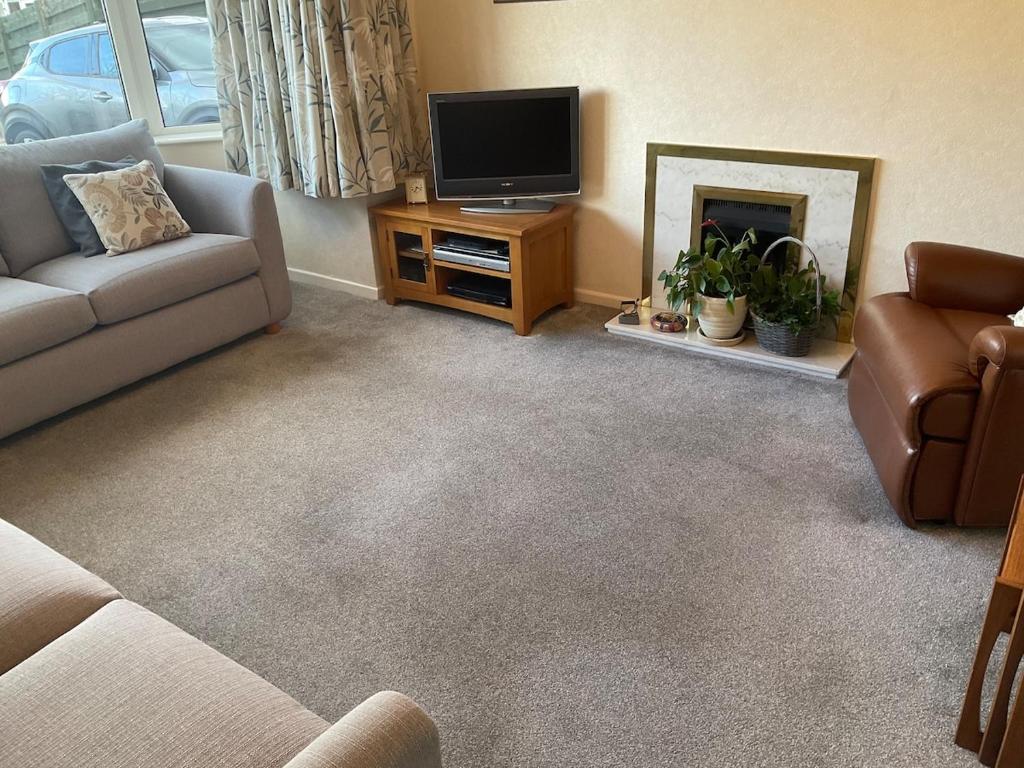 a living room with a couch and a tv and a fireplace at Cheshire 1 bedroom apartment - minimum 3 night stay please - garden view in Cheadle Hulme