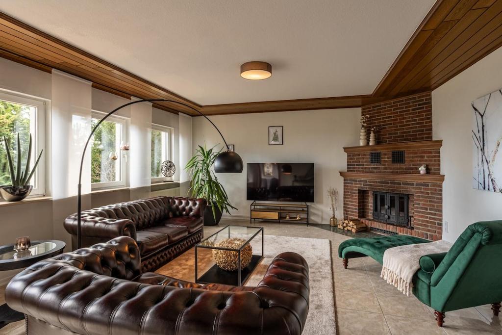 a living room with leather furniture and a fireplace at Green Eifel Casa in Feusdorf