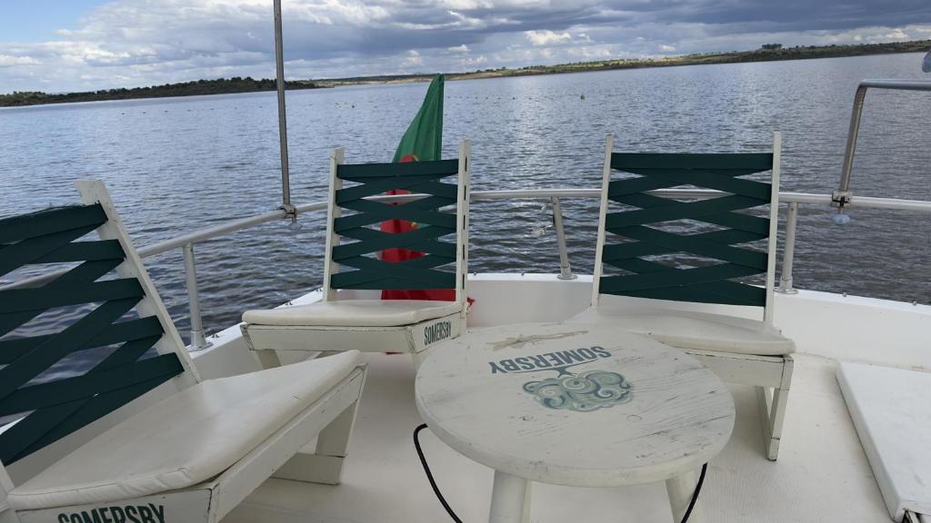 a boat with chairs and a table on the water at Iate Glória Sem-fim Monsaraz in Monsaraz