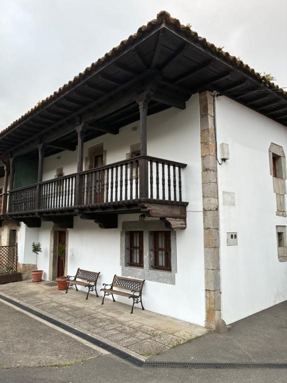 a white building with a balcony and two benches at rincón de covadonga in Caño