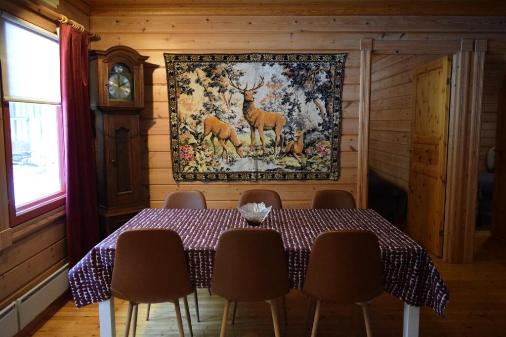 a dining room with a table and a tapestry on the wall at Poropelto Cottage in Ruhtinaansalmi