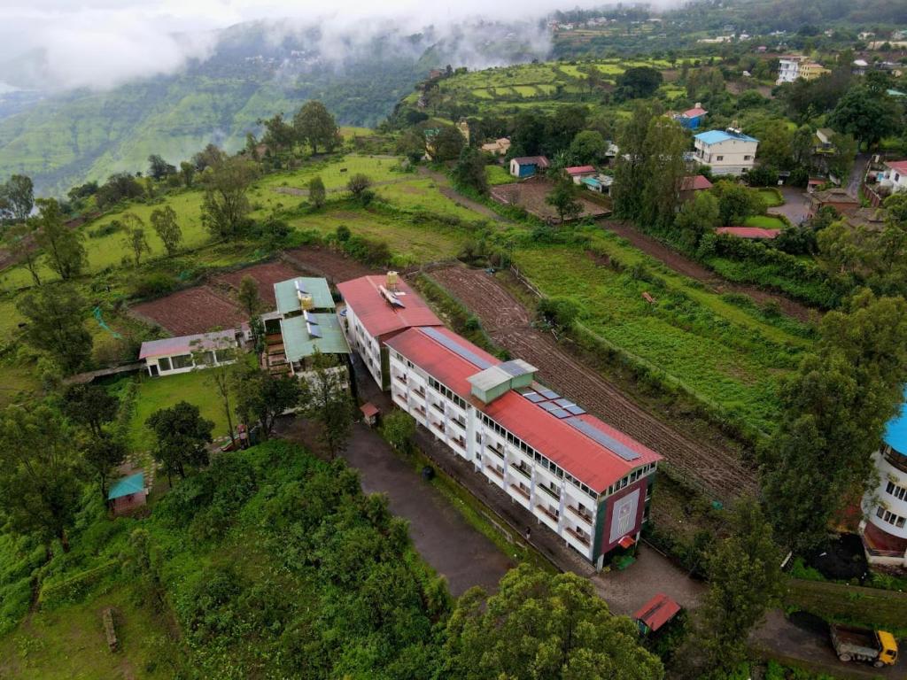 a building with a red roof on a hill at Harmony Palace in Mahabaleshwar