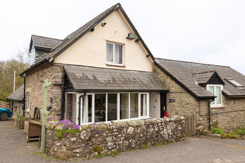 a stone house with a stone wall at Dunkery Cottage Wheddon Cross in Wheddon Cross