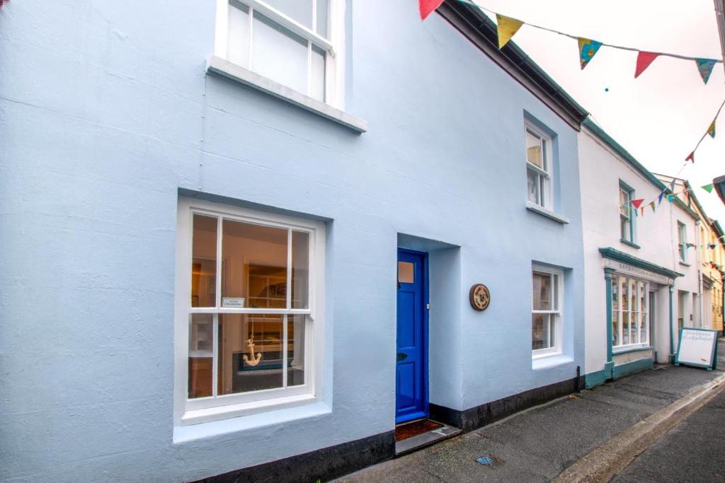 a white building with a blue door on a street at 3 Bed in Appledore oc-phoe in Appledore