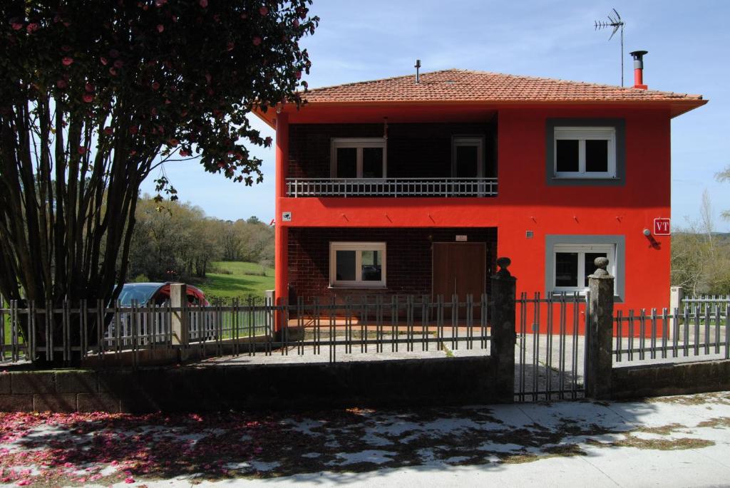 a red house with a fence in front of it at As Neveiras in Millerada