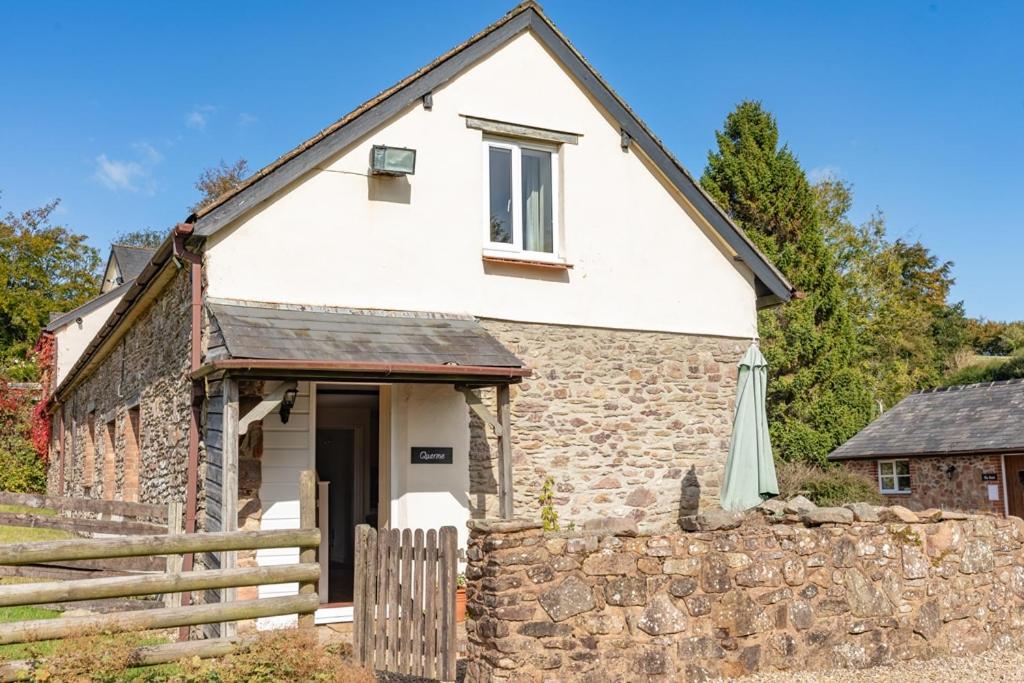 an old stone house with a stone wall at Quarme Cottage Wheddon Cross in Wheddon Cross