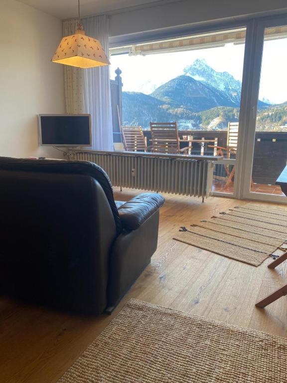 a living room with a couch and a large window at Appartement Raineck in Mittenwald