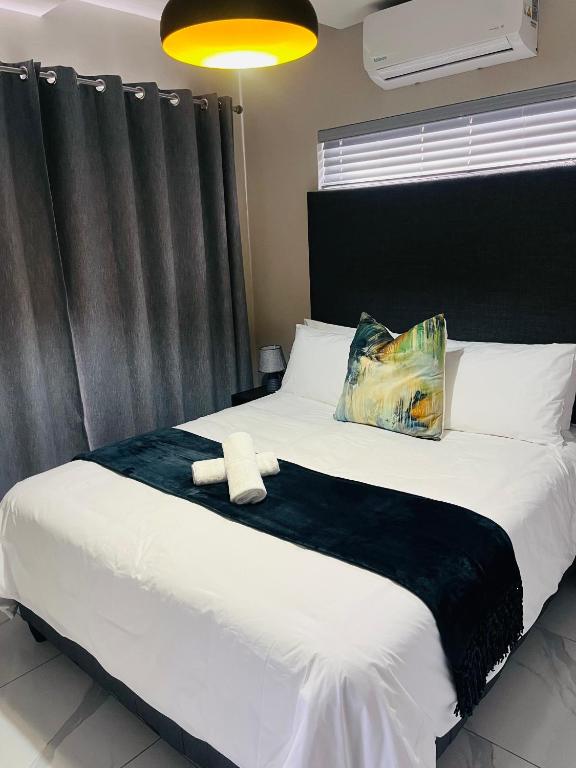 a bedroom with a large bed with a black headboard at Xitshavani Lodge in Phalaborwa