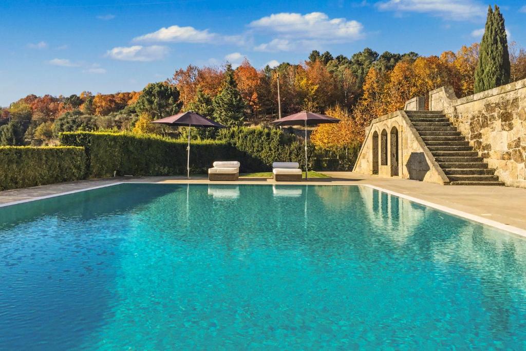 a swimming pool with two chairs and umbrellas at Quinta de Travanca - Casa da Eira in Baião