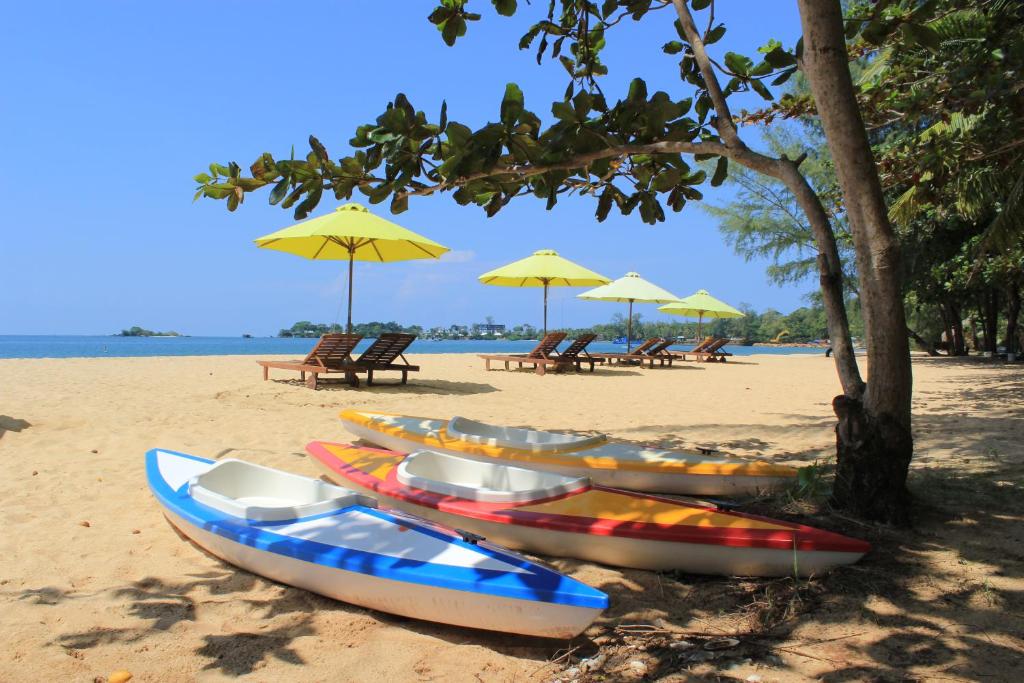 a row of kayaks on a beach with umbrellas at Vung Bau Resort in Phú Quốc
