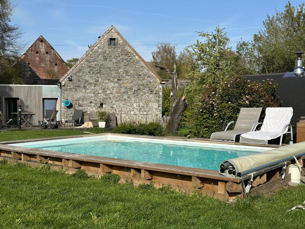 ein Swimmingpool in einem Garten mit zwei Stühlen und einem Haus in der Unterkunft Envoz-Zen in Héron