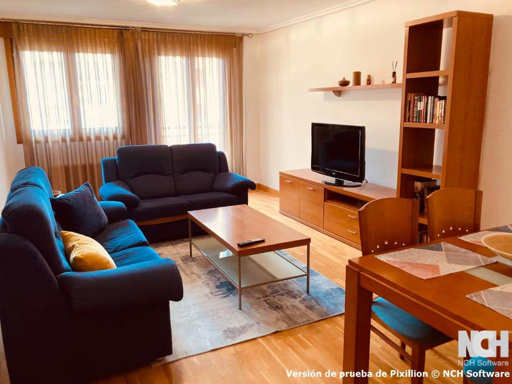 a living room with a blue couch and a tv at Duque de Ahumada 8 in Soria