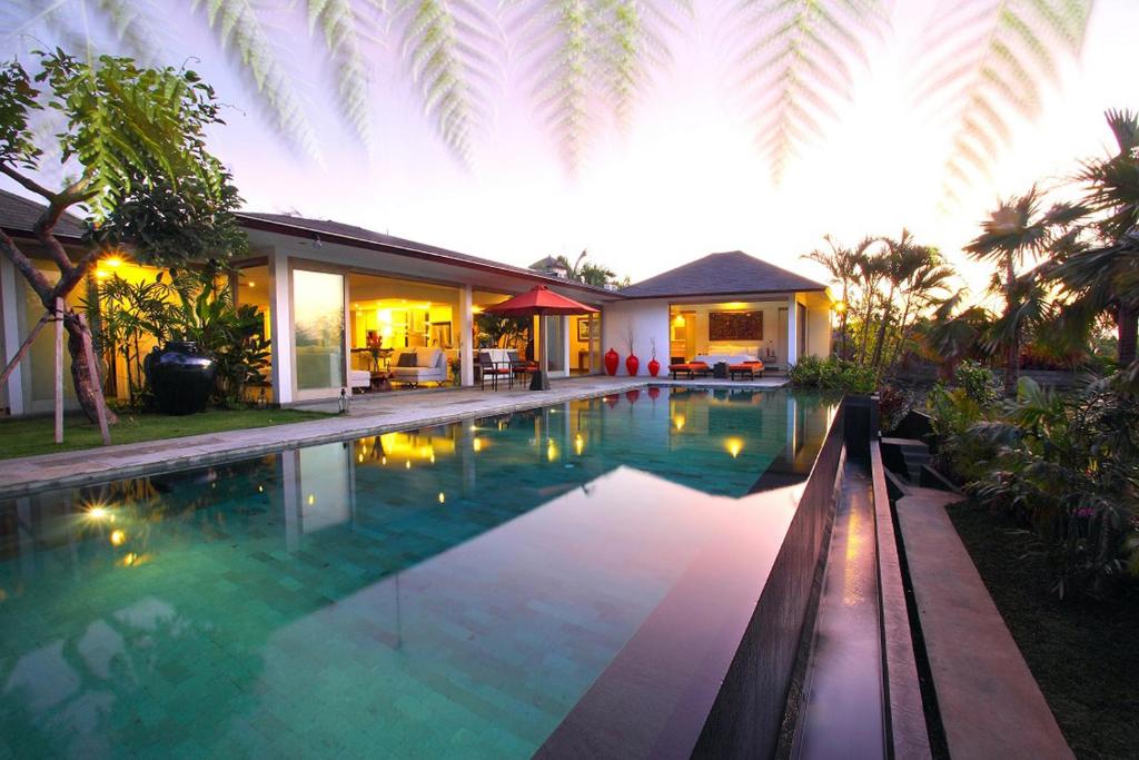 a swimming pool in front of a house at Amertha Villa Dreamland in Uluwatu