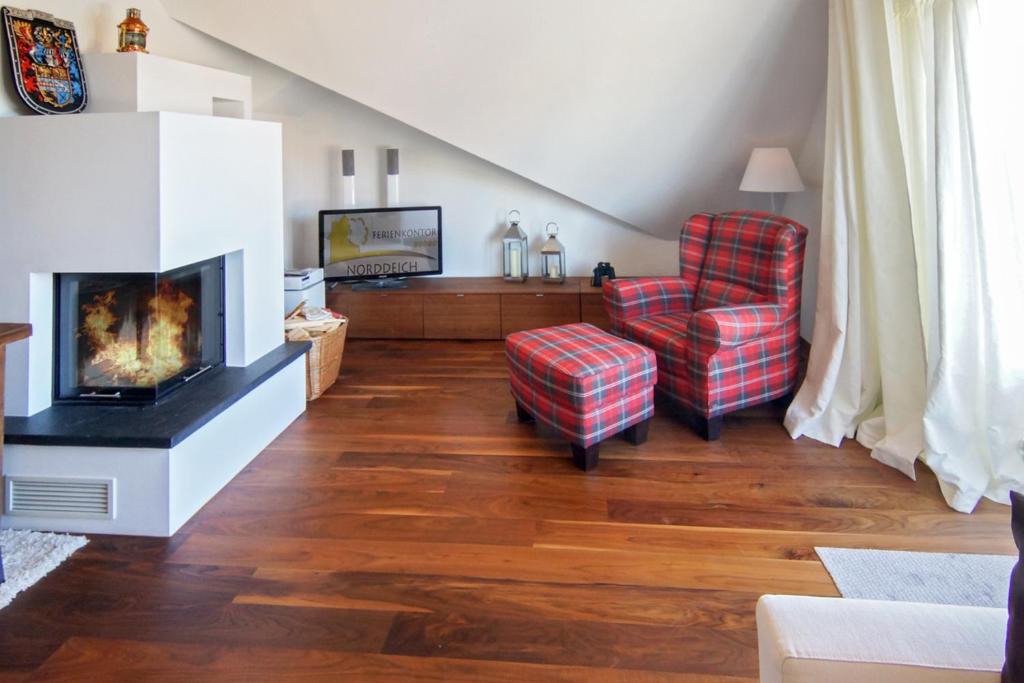 a living room with a fireplace and a chair at Ferienwohnung Loft in Strandnähe in Norden
