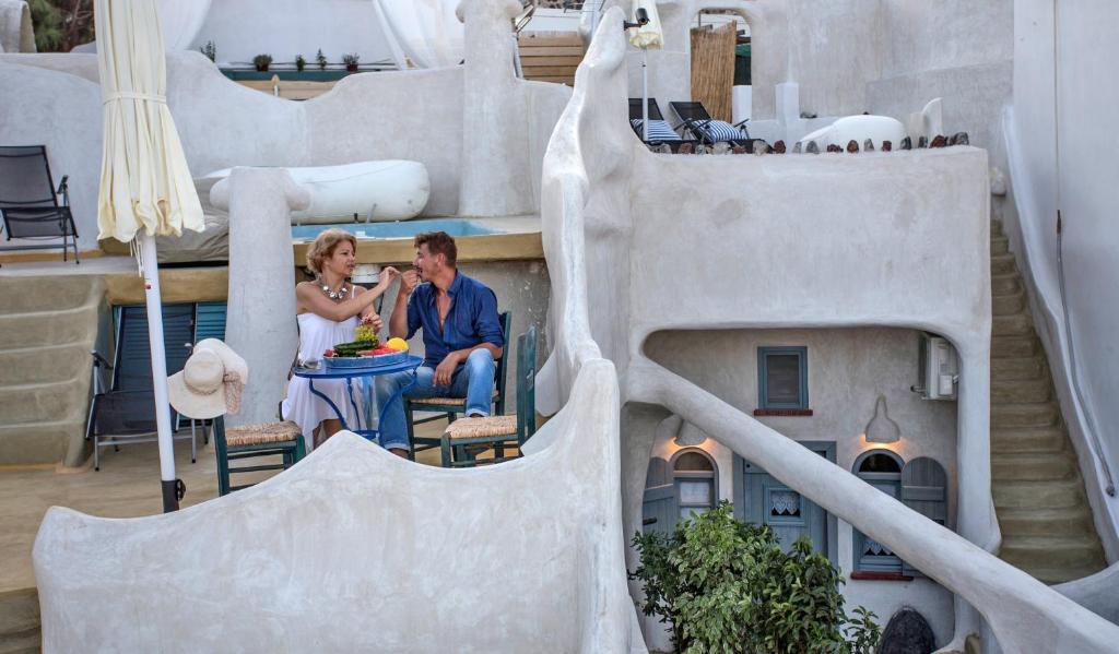 a man and woman sitting at a table on the balcony of a building at Αura Cave in Fira