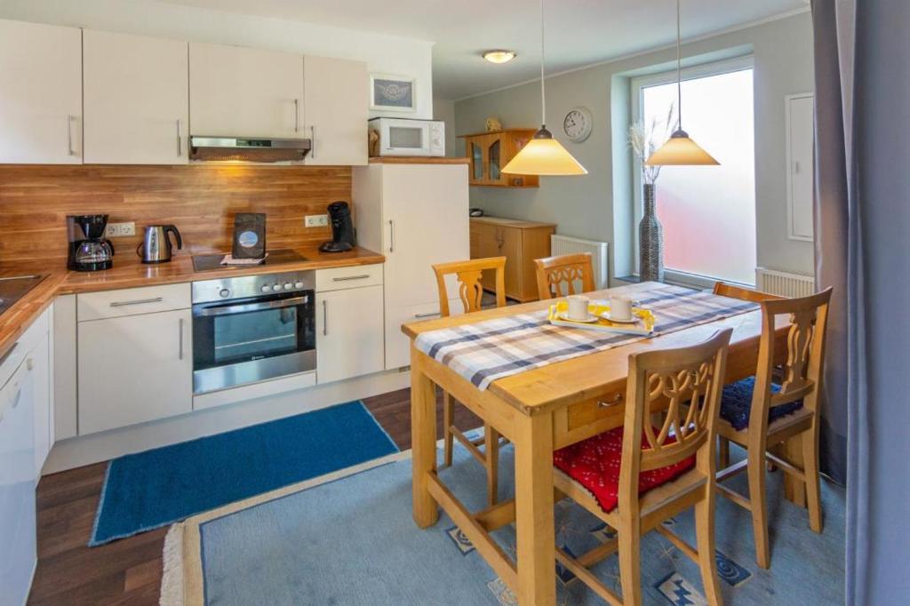 a kitchen with a wooden table with chairs and a dining room at Ferienhaus Mackeriege in Norden