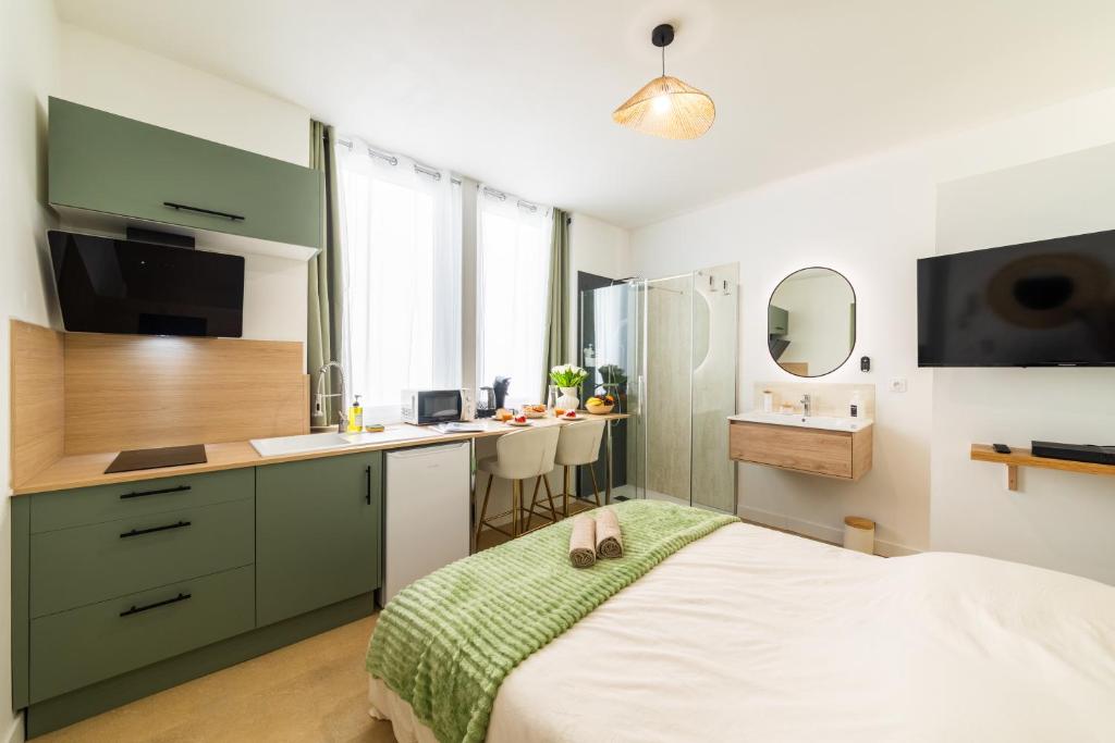 a bedroom with a bed and a kitchen with a sink at Le Sauge - Studio climatisé - Cocon rénové in Agen