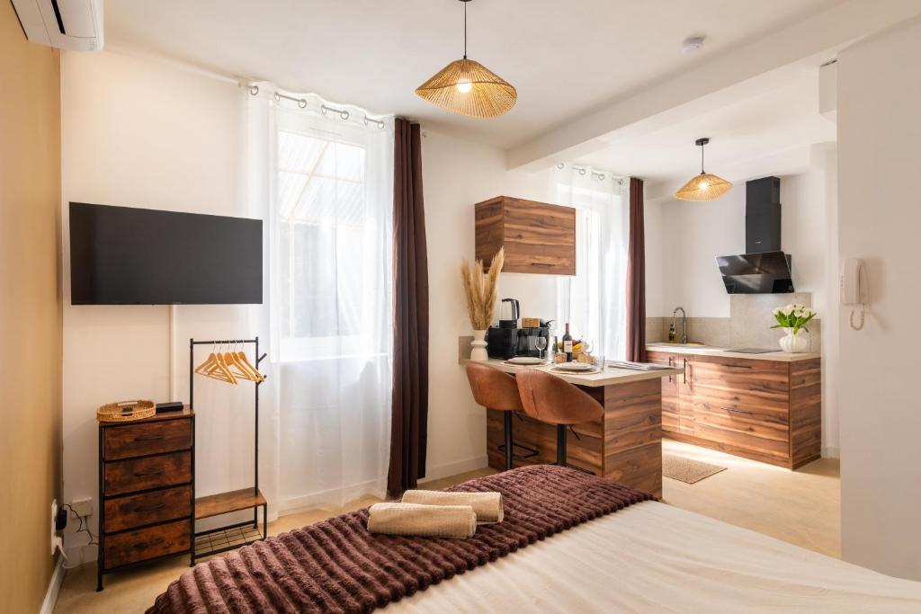 a bedroom with a bed and a sink and a kitchen at Le Brun - T1 climatisé - Terrasse et jardin privé in Agen