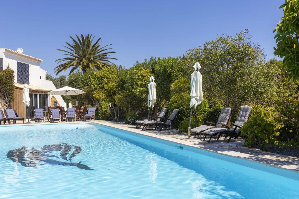 a swimming pool with chairs and umbrellas next to a house at Nice double bedroom in beautiful Quinta - QR06 in Lagos