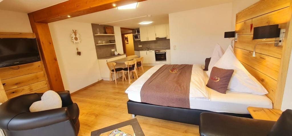 a bedroom with a large bed and a kitchen at Gästehaus Holzer Kreuz - Ferienwohnung "Narzisse" in Fröhnd