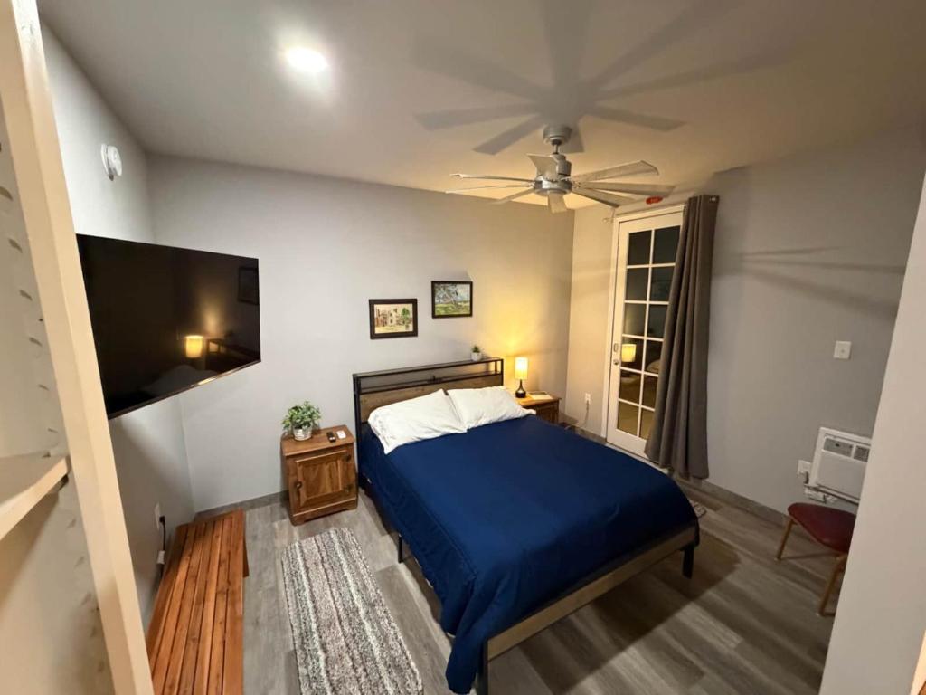 a bedroom with a blue bed and a flat screen tv at Germantown Inn & Lounge in Hermann