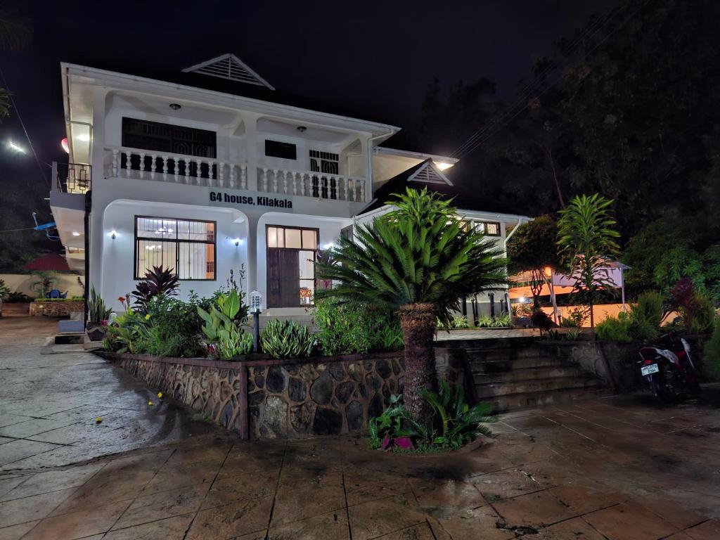 a white house with a palm tree in front of it at G4 homez in Morogoro