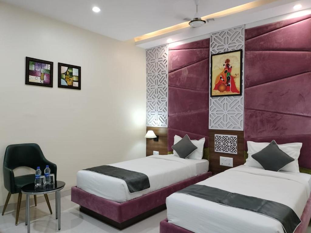 a hotel room with two beds and a chair at Hotel Vinayak International in Muzaffarpur
