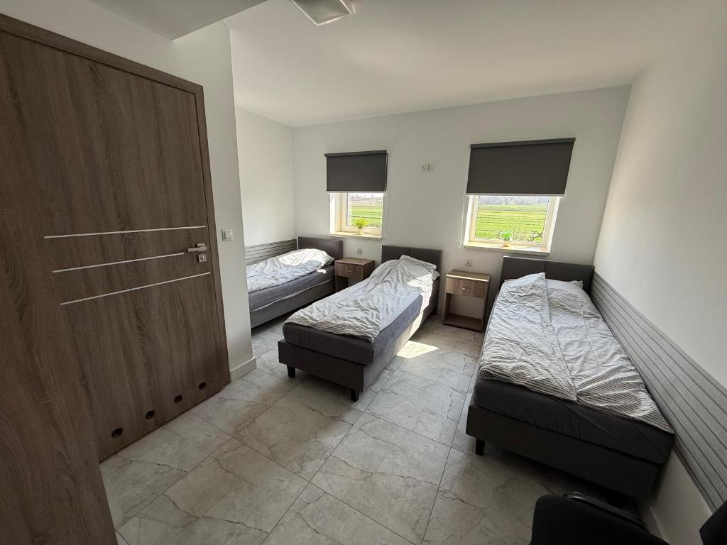 a room with two beds and a door and windows at Kwatery Smroków in Smroków